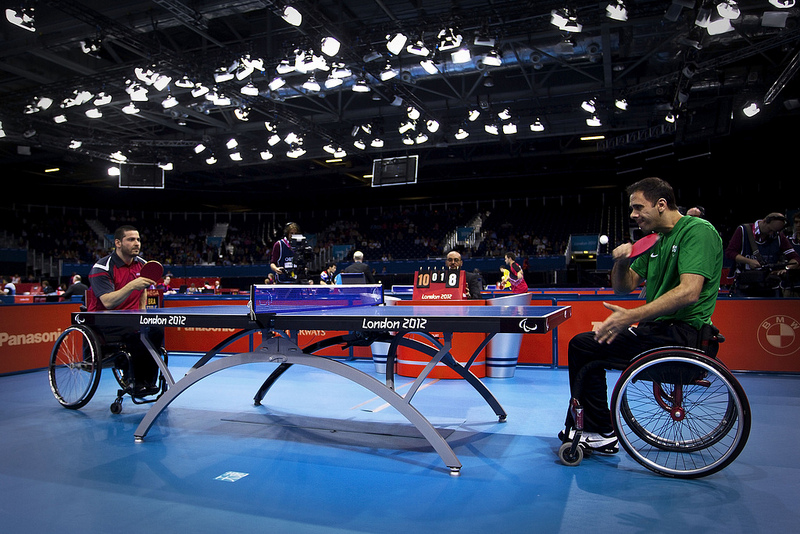 Dois atletas sobre cadeira de rodas em disputa no tenis de mesa