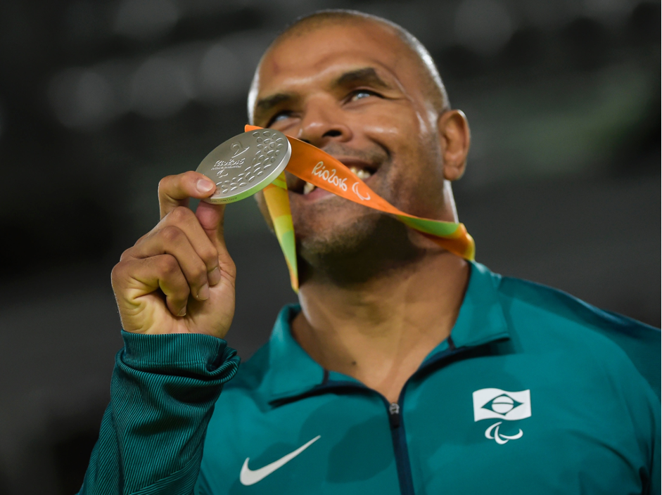 Foto de perfil de Antonio, um homem negro e careca. Ele está com sua medalha no pescoço e a carrega na altura do rosto com a ponta dos dedos, sorrindo. A fita da medalha indica que a ocasião foi nas Paralimpíadas Rio 2016.