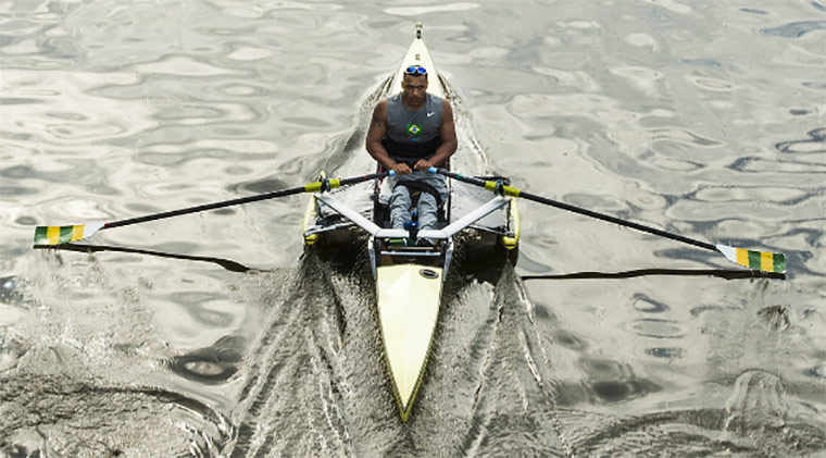 Foto de atleta visto do alto. Ele rema sobre a canoa