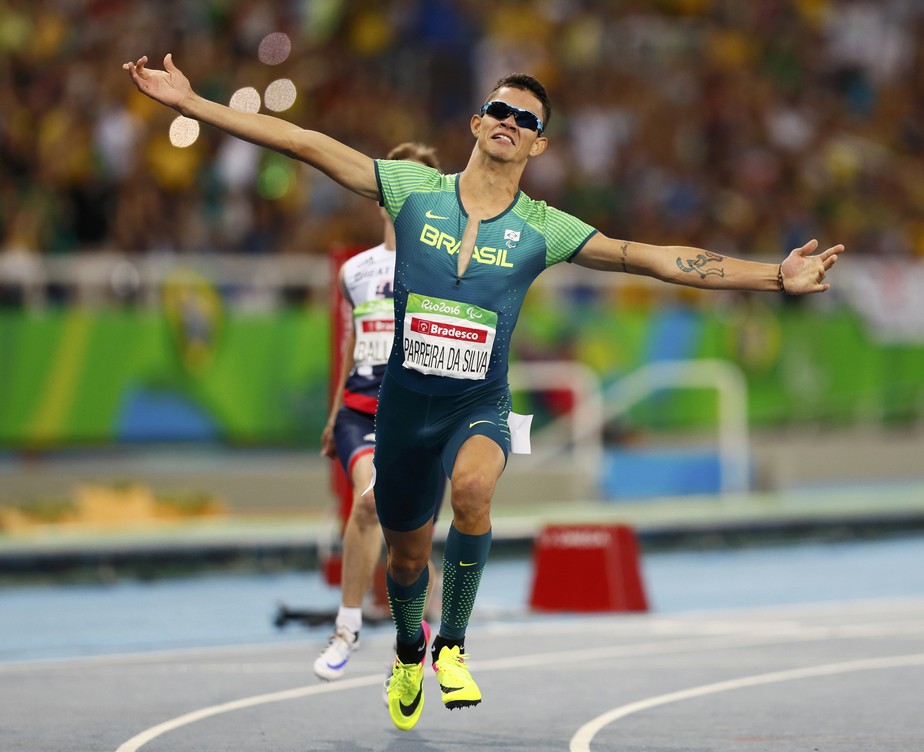 centro da imagem o atleta Rodrigo Parreira, com óculos escuro e uniforme do Time Brasil em ação nos Jogos Paralímpicos do Rio 2016.