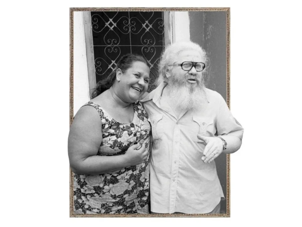 Imagem de um casal abraçado em frente a um portão.