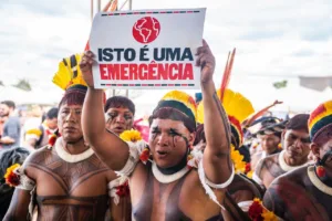 indígena segura placa escrito "Isto é uma emergência"