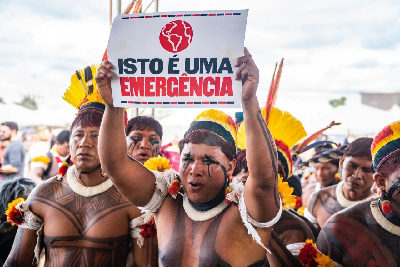 indígena segura placa escrito "Isto é uma emergência"