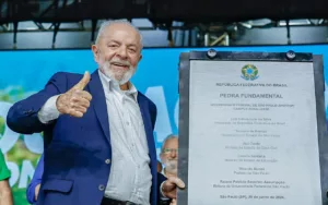 Lula ao lado de uma placa fazendo símbolo de joinha